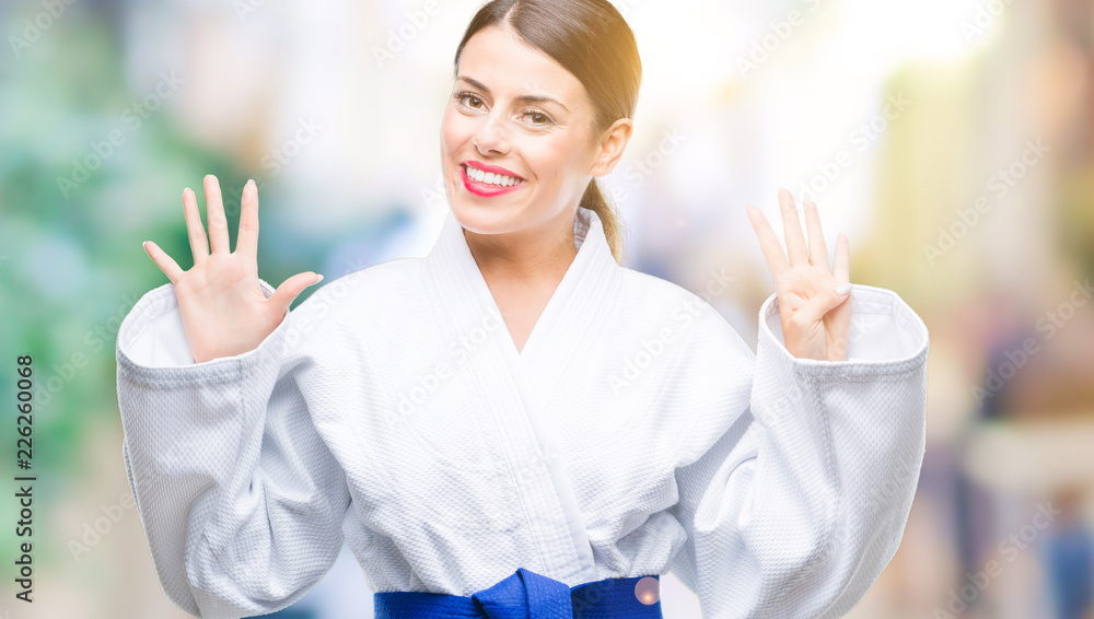 Young beautiful woman wearing karate kimono uniform over isolated background showing and pointing up with fingers number nine while smiling and happy. Stock Photo | Adobe Stock
