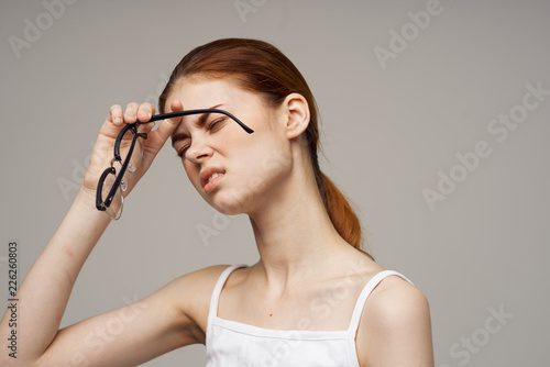 woman with headache holds glasses in her hand