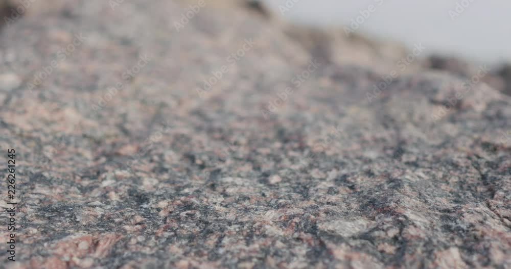 Handheld closeup slide over big granite rock Handheld closeup slide over big granite rock