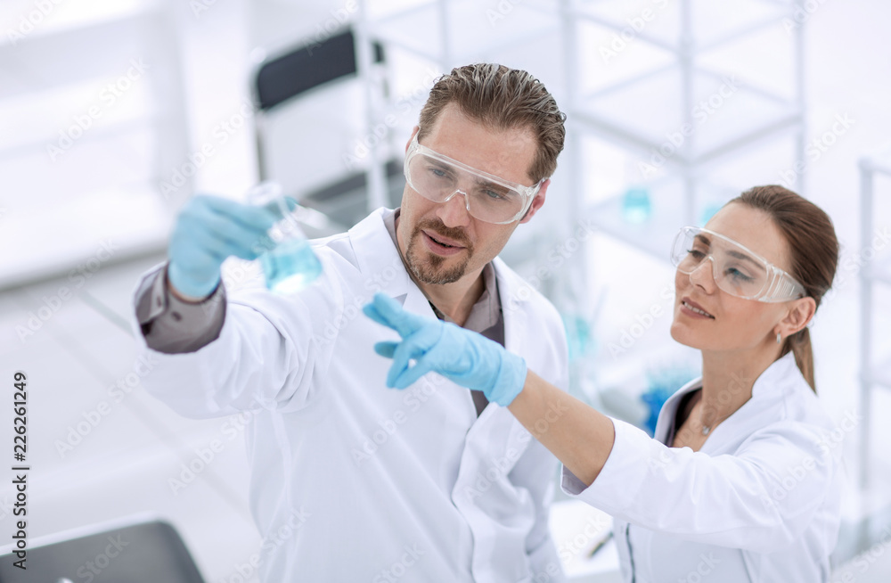 scientist and assistant look at the liquid in the flask scientist and assistant look at the liquid in the flask