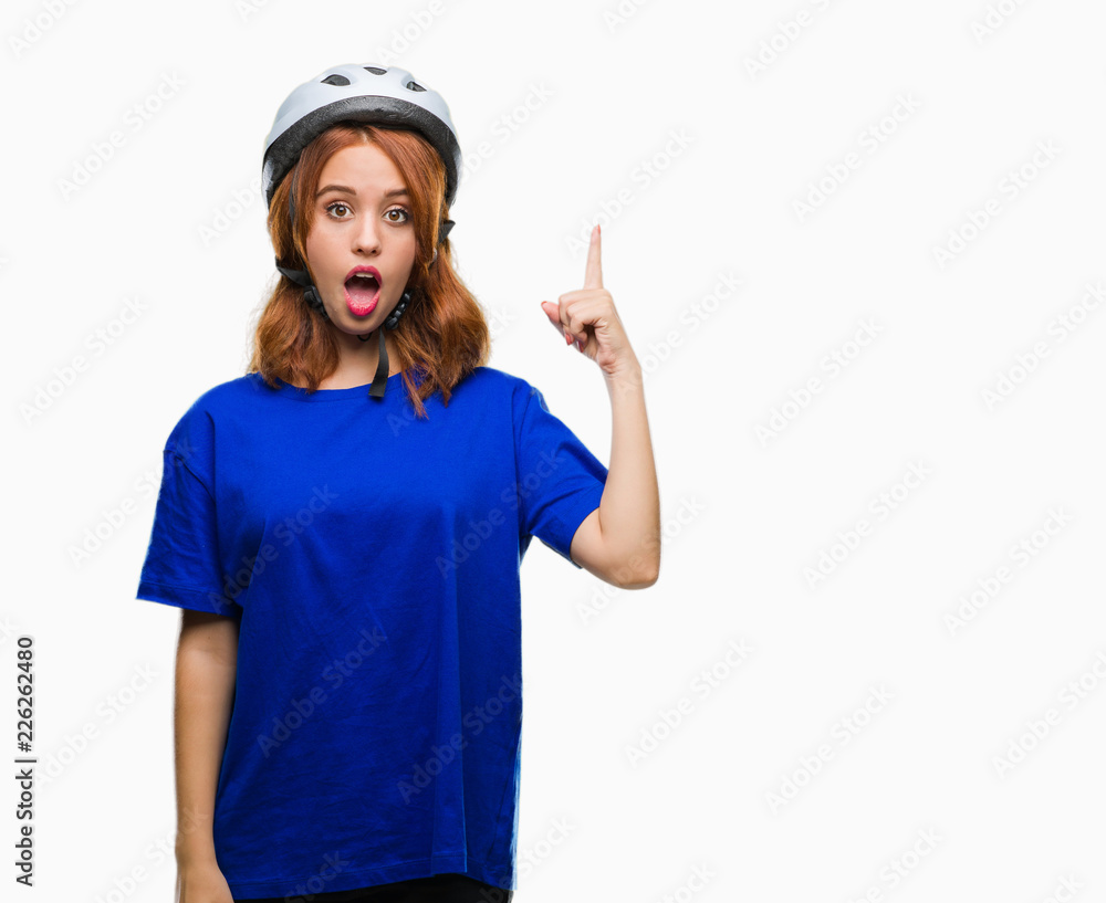 Young beautiful woman wearing cyclist helmet over isolated background pointing finger up with successful idea. Exited and happy. Number one. Young beautiful woman wearing cyclist helmet over isolated background pointing finger up with successful idea. Exited and happy. Number one.