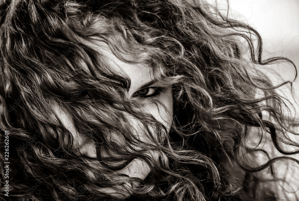 Close-up view at eyes of curly girl. Image in black and white color style Close-up view at eyes of curly girl. Image in black and white color style