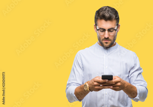 Young handsome man texting using smartphone over isolated background with a confident expression on smart face thinking serious
