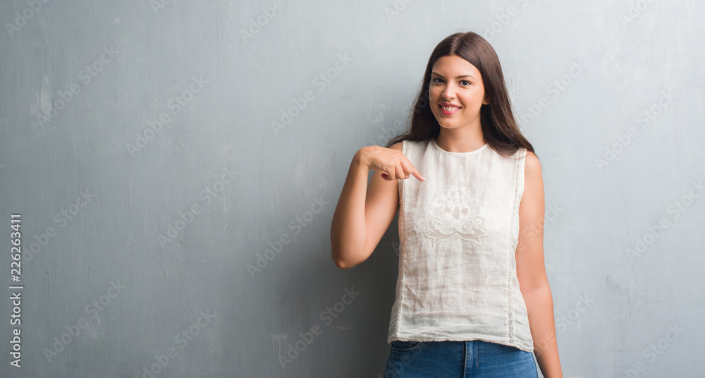 Young brunette woman over grunge grey wall with surprise face pointing finger to himself Young brunette woman over grunge grey wall with surprise face pointing finger to himself