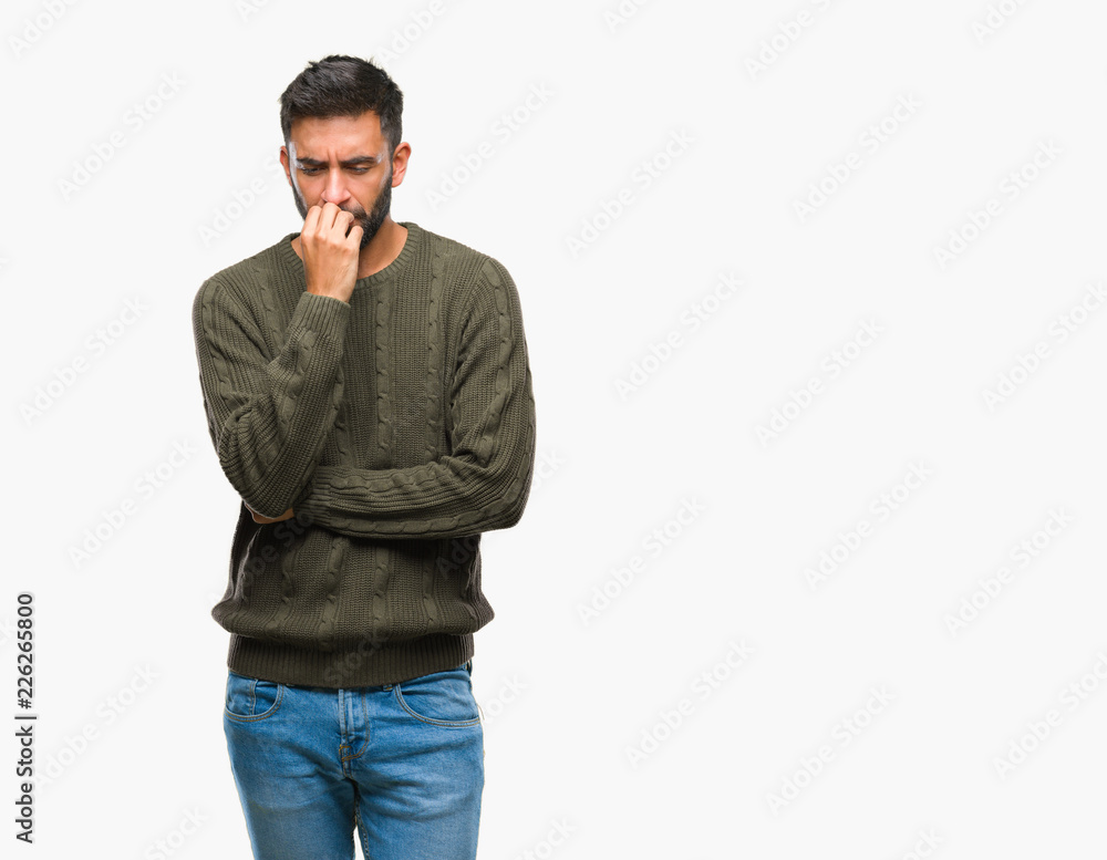 Adult hispanic man wearing winter sweater over isolated background looking stressed and nervous with hands on mouth biting nails. Anxiety problem. Adult hispanic man wearing winter sweater over isolated background looking stressed and nervous with hands on mouth biting nails. Anxiety problem.