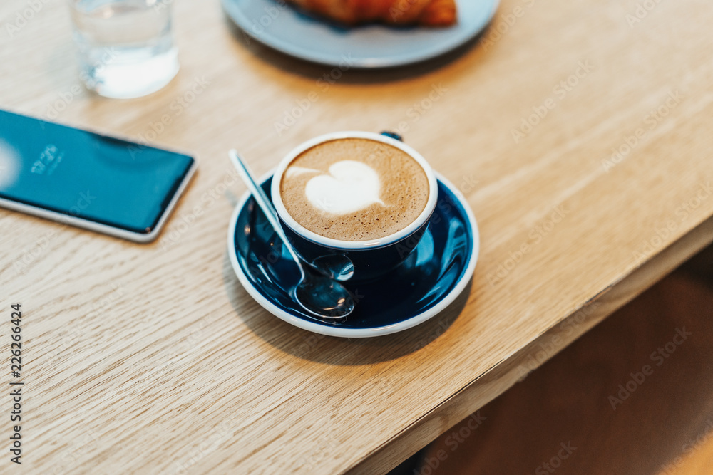 Obraz premium Close up of coffee cup on wooden table in cafe. Concept of tasty breakfast.
