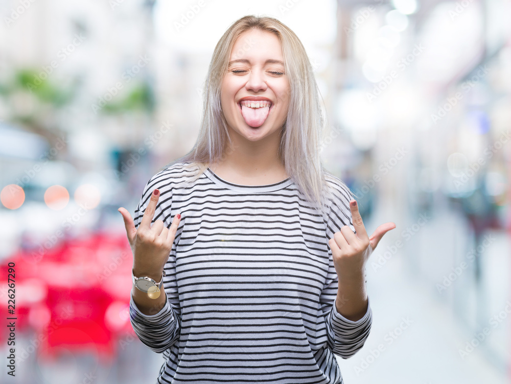 Young blonde woman over isolated background shouting with crazy expression doing rock symbol with hands up. Music star. Heavy concept.