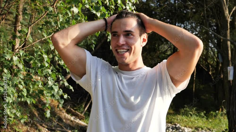 Young handsome happy man standing in nature, smiling and laughing while looking at camera Young handsome happy man standing in nature, smiling and laughing while looking at camera