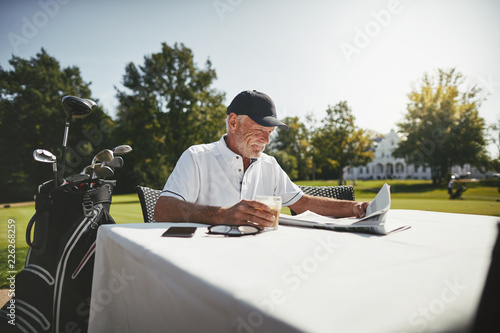 Senior man relaxing with coffee at his golf clubhouse photo