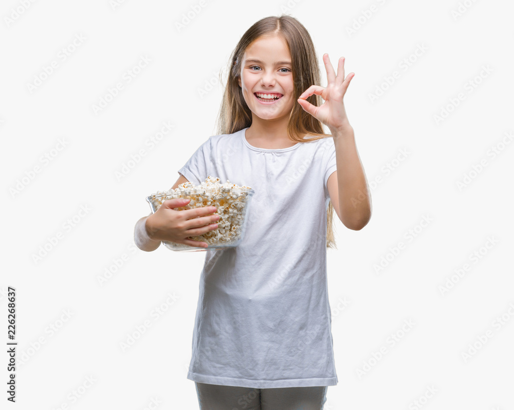 Young beautiful girl eating popcorn snack isolated background doing ok sign with fingers, excellent symbol Young beautiful girl eating popcorn snack isolated background doing ok sign with fingers, excellent symbol