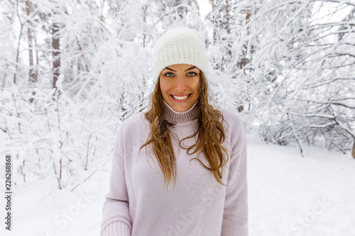 красивая девушка в розовом свитере и белая шляпа в снежном лесу счастлива