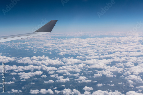 An airbus wing while flying over some clouds.