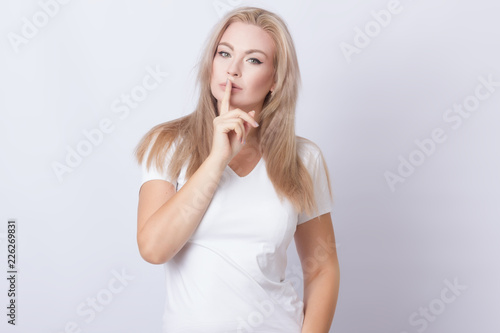 Image of beautiful blonde woman holding finger near her lips