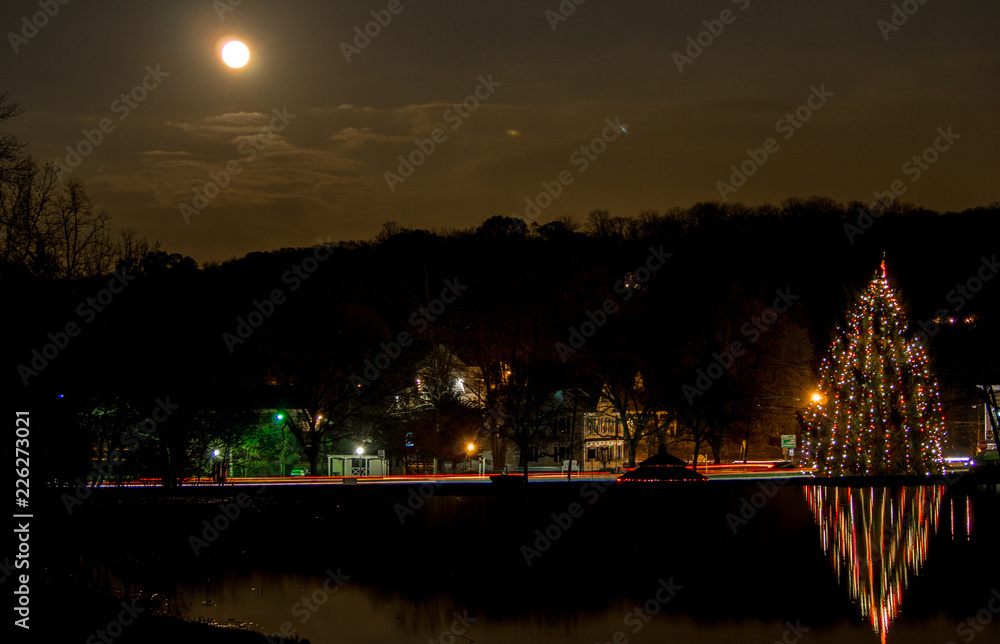 full moon above lake with Christmas tree