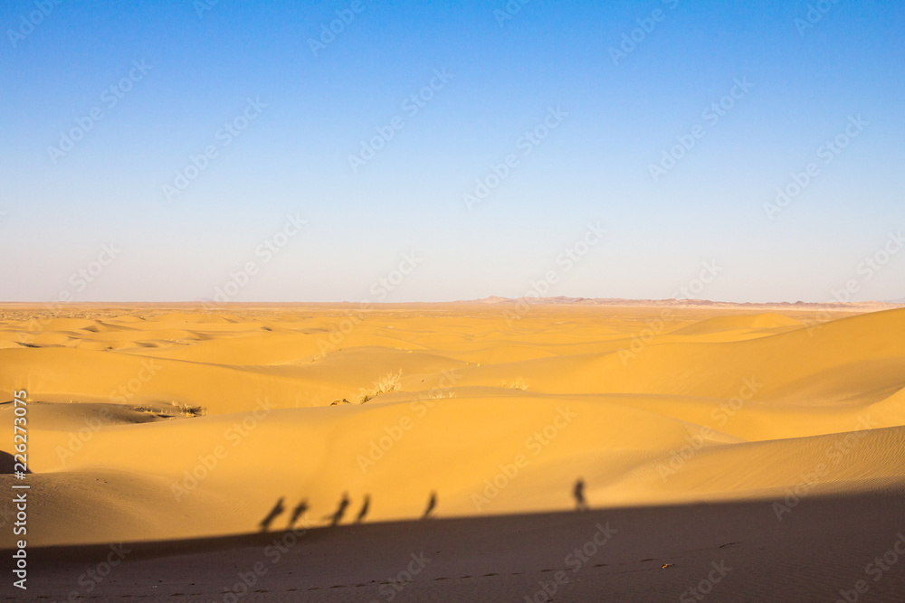 Sand dunes in the Maranjab desert, near Kashan, Iran, at sunset, with the shape and shadows of people, tourists, walking. maranjab desert is one of the main landmarks of the region Sand dunes in the Maranjab desert, near Kashan, Iran, at sunset, with the shape and shadows of people, tourists, walking. maranjab desert is one of the main landmarks of the region
