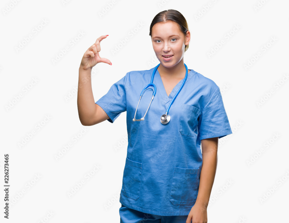 Young caucasian doctor woman wearing medical uniform over isolated background smiling and confident gesturing with hand doing size sign with fingers while looking and the camera. Measure concept. Young caucasian doctor woman wearing medical uniform over isolated background smiling and confident gesturing with hand doing size sign with fingers while looking and the camera. Measure concept.