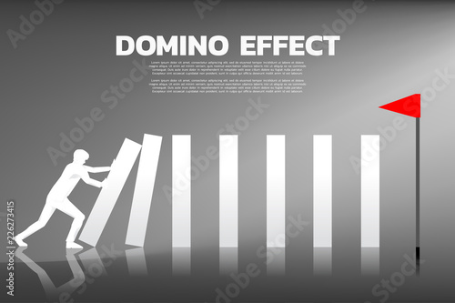 Silhouette of businessman pushing the block to create domino effect to hit the goal. business concept of try to make the domino effect
