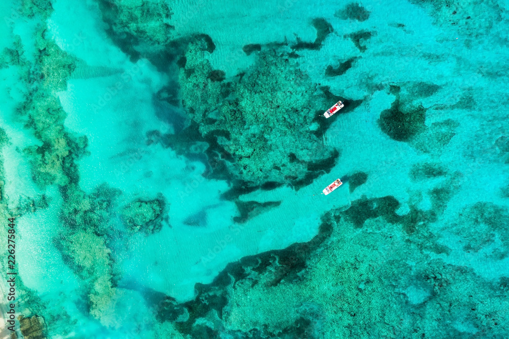 Aerial top view of two empty boats on bright ocean water with colar reefs