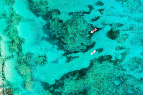 Aerial top view of two empty boats on bright ocean water with colar reefs