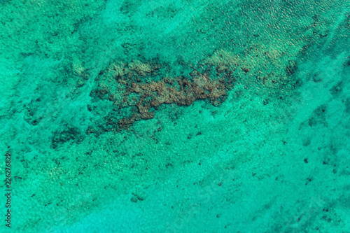 Top view of bright ocean water with reefs. Nature summer background