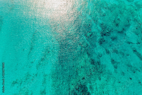 Aerial top view of clear ocean water with reefs and sunshine. Nature background