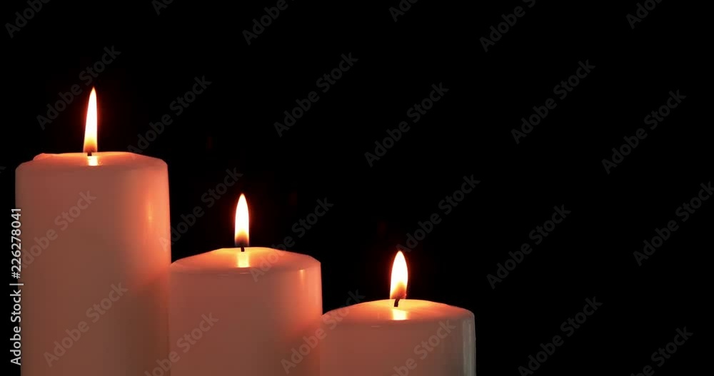 White Christmas candles with golden light blowing by wind on dark background. Shot in 4k resolution White Christmas candles with golden light blowing by wind on dark background. Shot in 4k resolution
