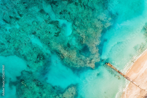 Top aerial view of the beach and clear ocean water with coral reefs. Summer background