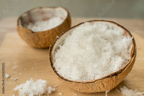 Close up of Freshly grated coconut in shell on wood table.