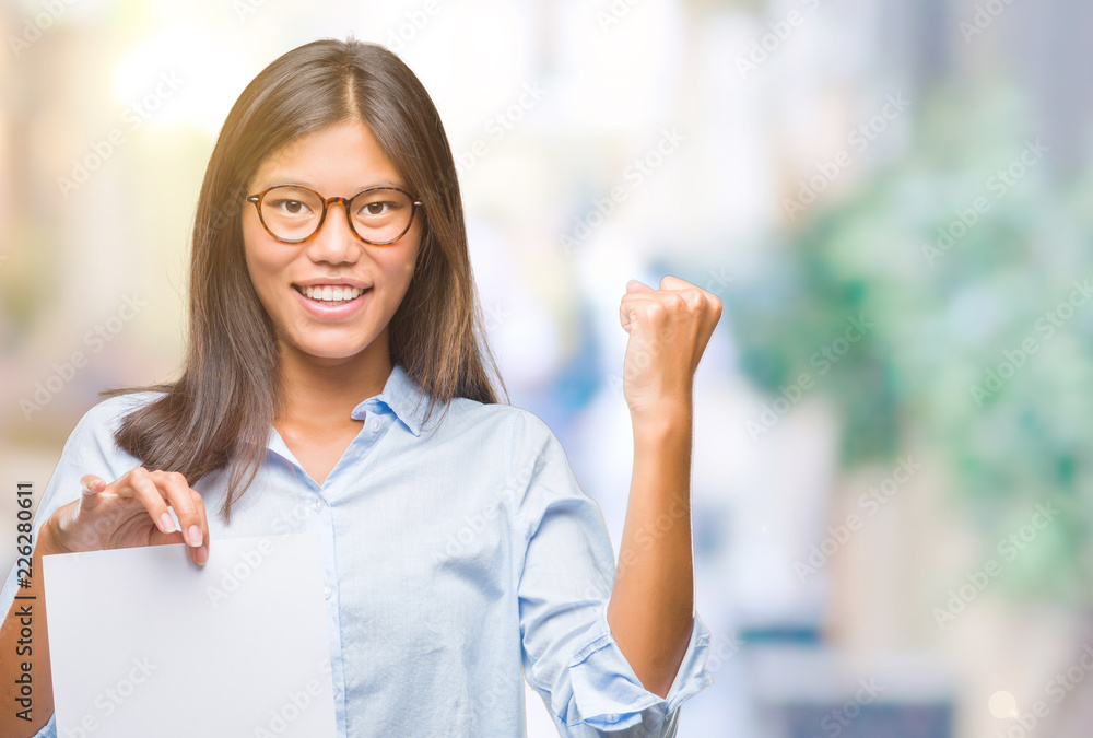 Young asian woman over isolated background holding blank paper screaming proud and celebrating victory and success very excited, cheering emotion Young asian woman over isolated background holding blank paper screaming proud and celebrating victory and success very excited, cheering emotion