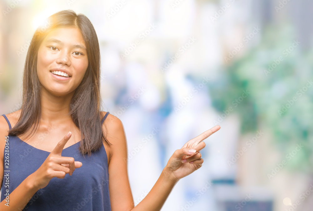 Young asian woman over isolated background smiling and looking at the camera pointing with two hands and fingers to the side. Young asian woman over isolated background smiling and looking at the camera pointing with two hands and fingers to the side.