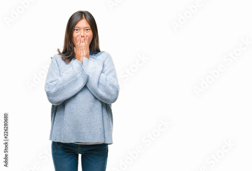 Young asian woman wearing winter sweater over isolated background shocked covering mouth with hands for mistake. Secret concept. © Krakenimages.com