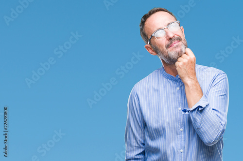 Middle age hoary senior man wearing glasses over isolated background with hand on chin thinking about question, pensive expression. Smiling with thoughtful face. Doubt concept.