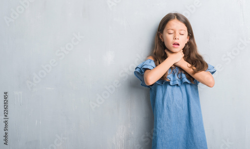 Foto Young hispanic kid over grunge grey wall shouting and suffocate because painful strangle