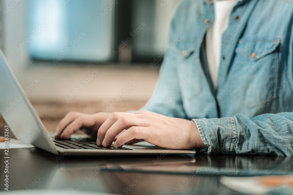 Fototapeta premium Professional freelancer. Close up of a nice smart handsome man typing on the keyboard while working at the laptop
