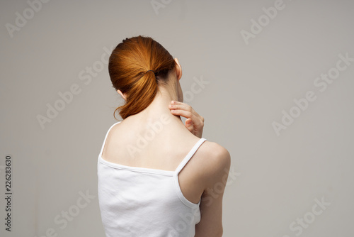 woman stands with her back and holds her hand around her neck