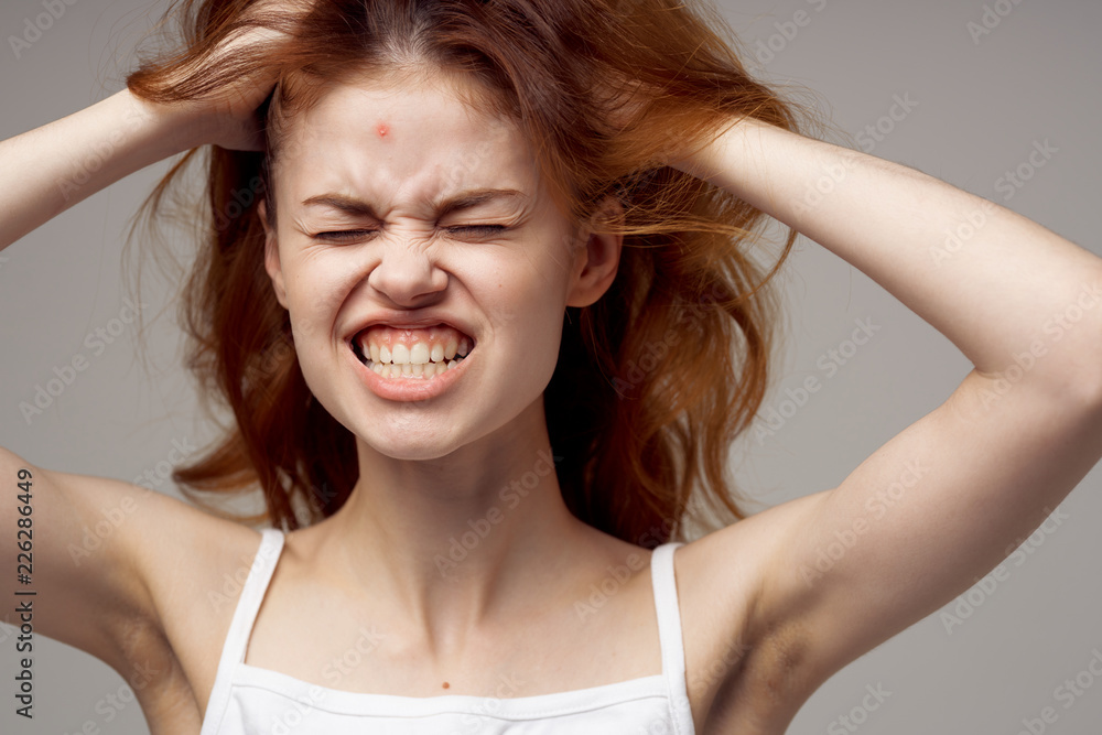a woman with a pimple on the forehead narrows her eyes and holds her hair a woman with a pimple on the forehead narrows her eyes and holds her hair