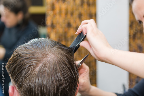 Scissor the hair of a man in a barbershop © Sergey_Siberia88
