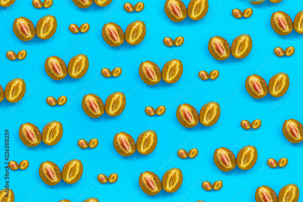 Food pattern of halves of ripe blue plum with bone on bright turquoise paper, minimalism style, top view
