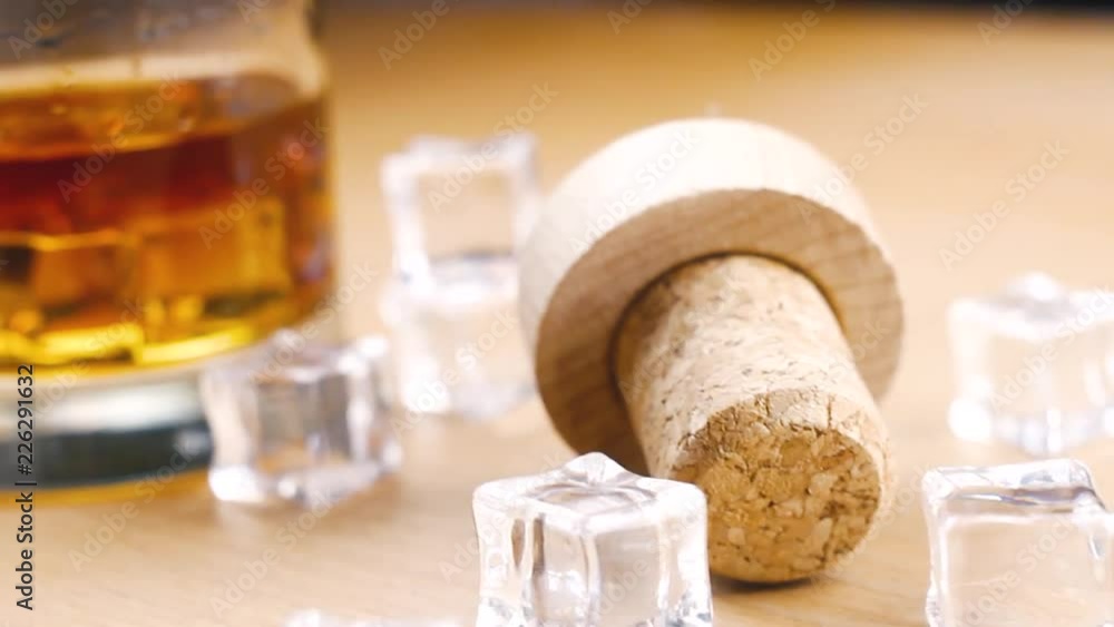 Whiskey bottle with crystal glass and ice cubes on wooden surface. Close up. Whiskey bottle with crystal glass and ice cubes on wooden surface. Close up.