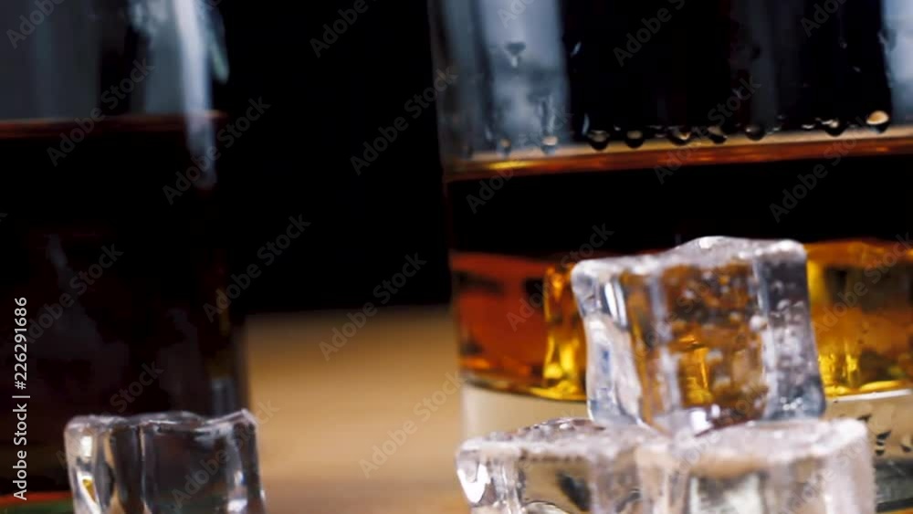 Crystal whiskey glass with bottle and ice cubes. Close up. Crystal whiskey glass with bottle and ice cubes. Close up.