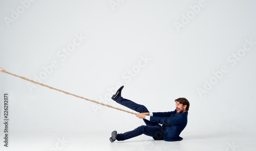 man in a suit lying on the floor and pulling on the rope