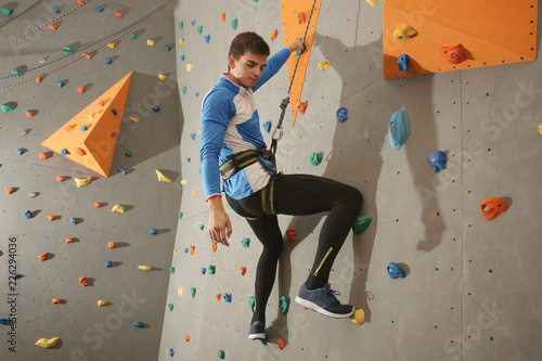 Young sporty man training in climbing gym