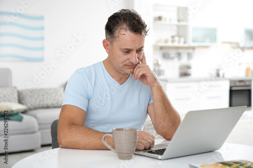 Handsome mature man with laptop at home