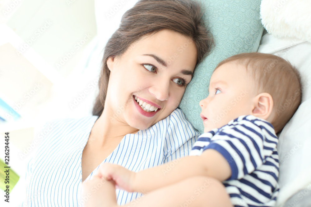 Loving mother and her baby lying on bed at home Loving mother and her baby lying on bed at home