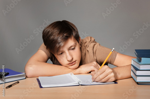 Tired teenager boy doing ho...