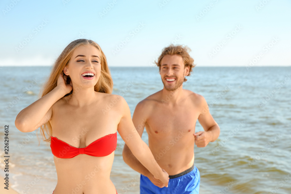 Happy young couple in beachwear having fun on seashore Happy young couple in beachwear having fun on seashore