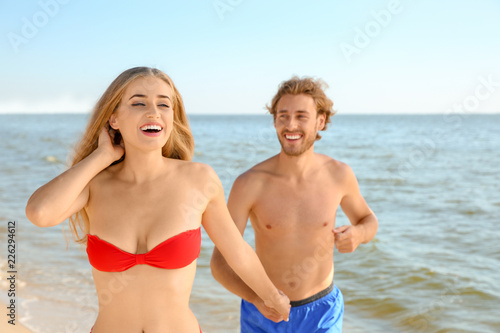 Happy young couple in beachwear having fun on seashore