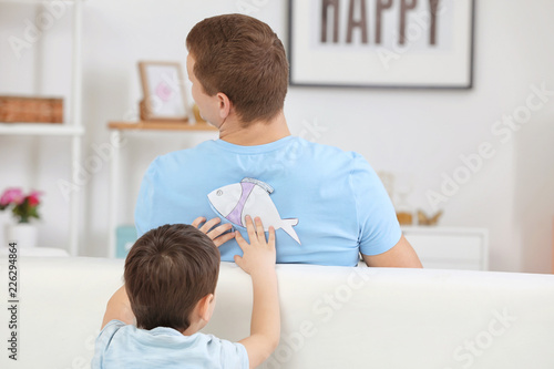 Little boy sticking paper f...