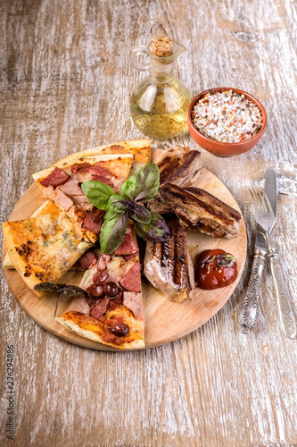 Pizza and meat on a round cutting board. Vertical shot