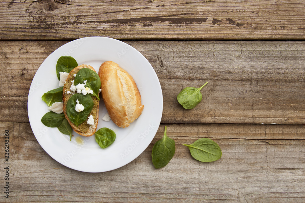 Healthy snack. Bun or bread with pesto pasta and basil leaves. Rustic wooden table, top view. Healthy snack. Bun or bread with pesto pasta and basil leaves. Rustic wooden table, top view.